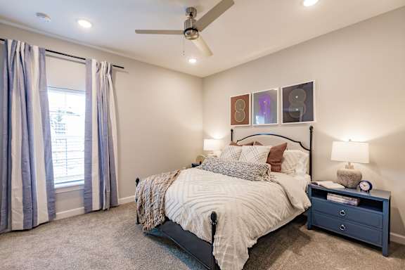 A bedroom with a large bed and a ceiling fan.