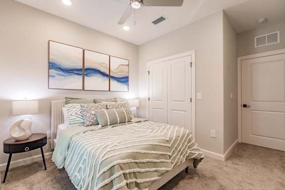 A bedroom with a bed, a nightstand, and a painting on the wall.
