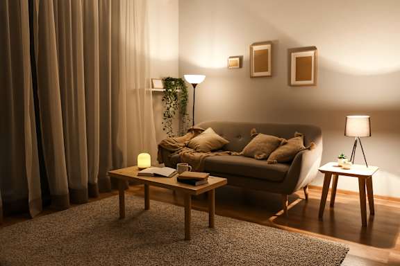 A cozy living room with a couch, a table, and a lamp.