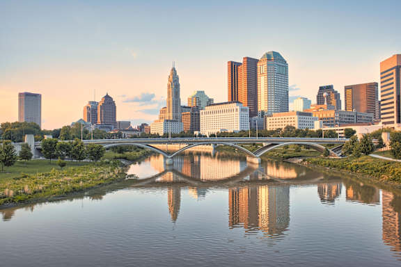 A city skyline is reflected in a body of water.