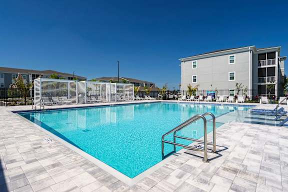 A large swimming pool surrounded by a tiled floor and a metal ladder.