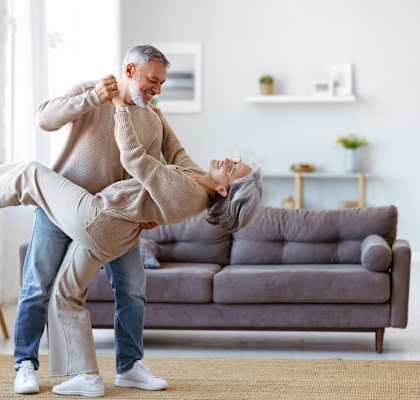 A man is helping a woman to stretch her leg while they are in a living room.