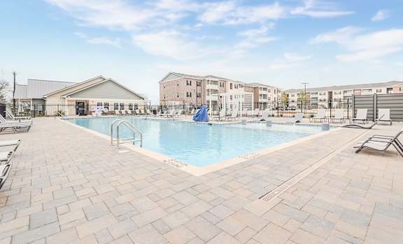 A large outdoor swimming pool surrounded by a brick patio.
