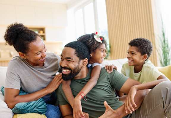 A family of four is sitting on a couch together.