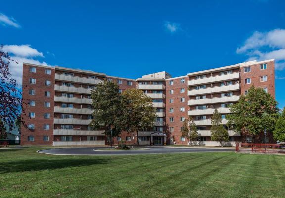 an apartment building on the corner of a green lawn