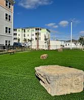 a fenced in dog park with large rocks and a bench