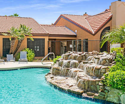 a swimming pool with a waterfall in front of a house