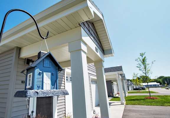 A blue birdhouse is hanging from a wire on a house.