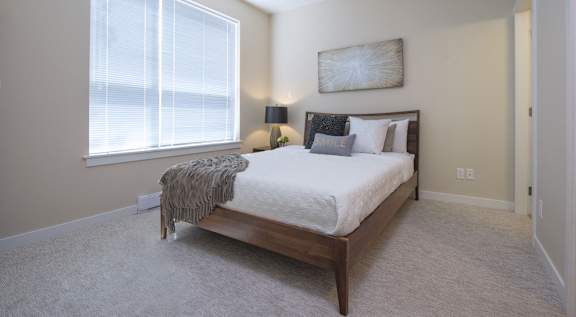 A bedroom with a bed, two lamps, and a window.