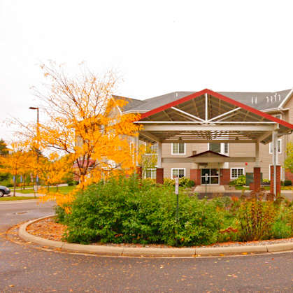 A large building with a red roof and a circular driveway in front.