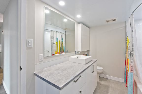 A bathroom with a white vanity and a mirror above it.