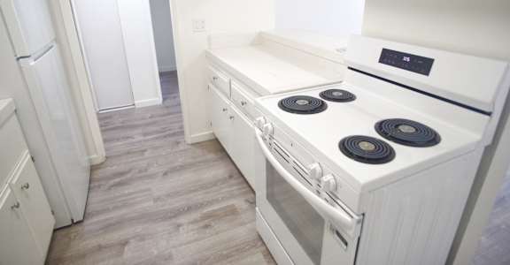 A white stove top oven with four burners and a stainless steel oven door.