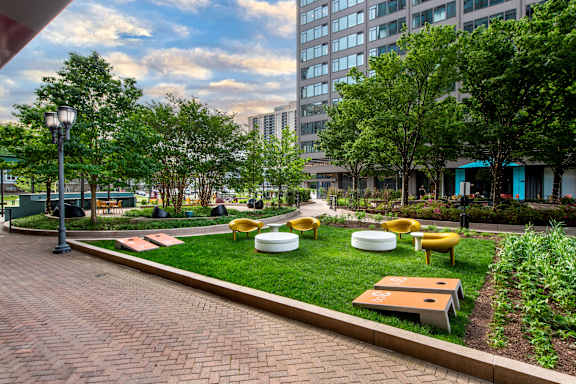 A park with a brick walkway, green grass, and trees.