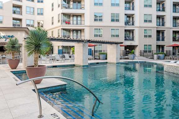 A pool in front of a building with a palm tree.