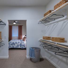 a walk in closet with shelves and racks and a bedroom with a bed