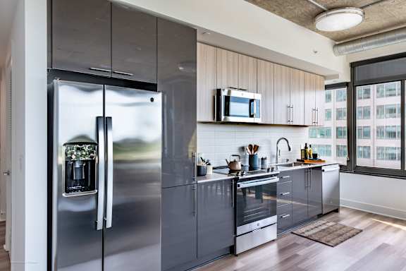 A modern kitchen with a stainless steel refrigerator and wooden cabinets.