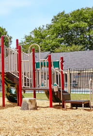 a playground with two slides and a picnic table in front of a building