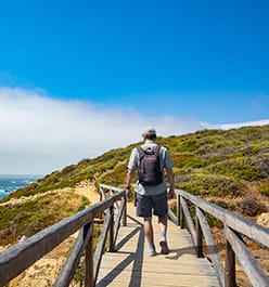 stock photo: man walking down a wooden path to the beach