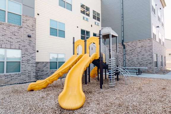 A yellow slide in the middle of a playground.