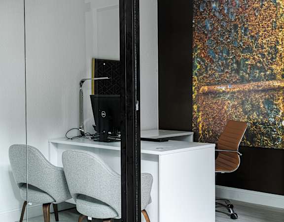 a room with a desk and two chairs and a large painting on the wall
