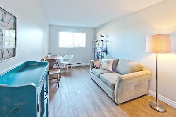 A living room with a blue cabinet, a white chair, a grey couch, and a floor lamp.