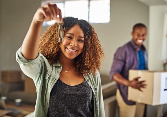 a woman is holding up her hair in a room with a man holding a box