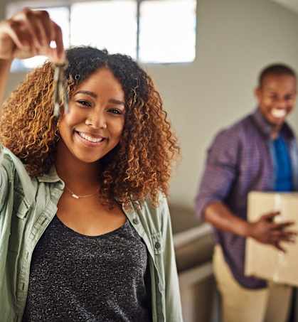 a woman is holding up her hair in a room with a man holding a box