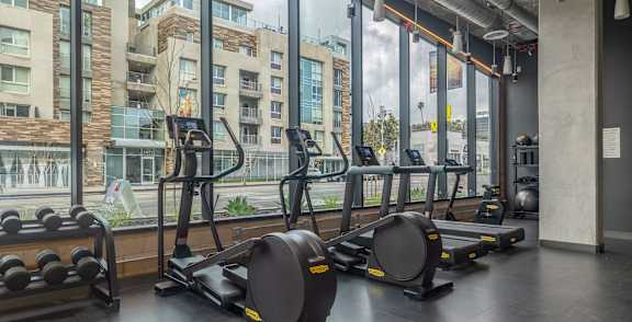 A gym with a view of apartment buildings outside the window.