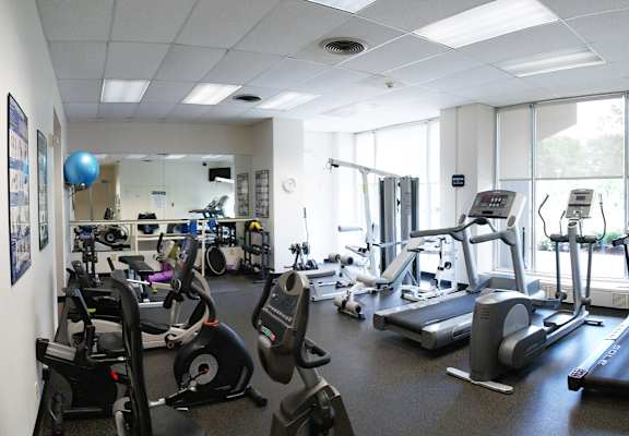 A gym with a variety of exercise equipment including treadmills, stationary bikes, and weight machines.