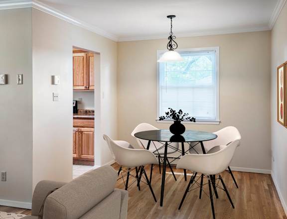 A dining room with a round table and white chairs at Rivercrest Apartments, New Jersey