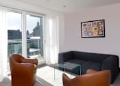 Thumbnail 5 of 5 - a living room with a black couch and a glass coffee table