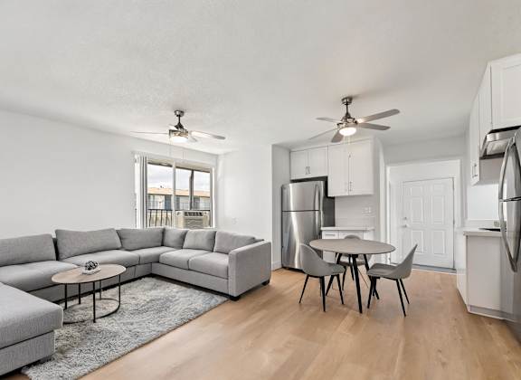 A modern kitchen with a grey sofa and a dining table.
