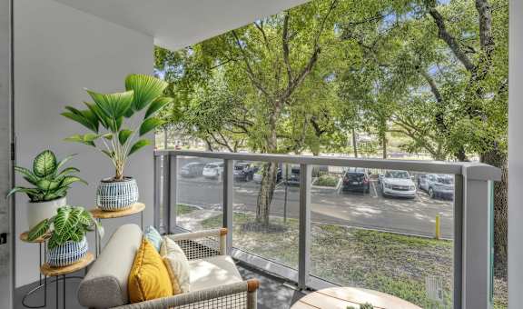 A balcony with a couch, plants and a view of a street.