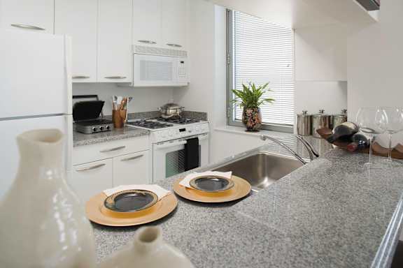 A kitchen with a white fridge, microwave, and stove top oven.at 'The Metropolis', New York