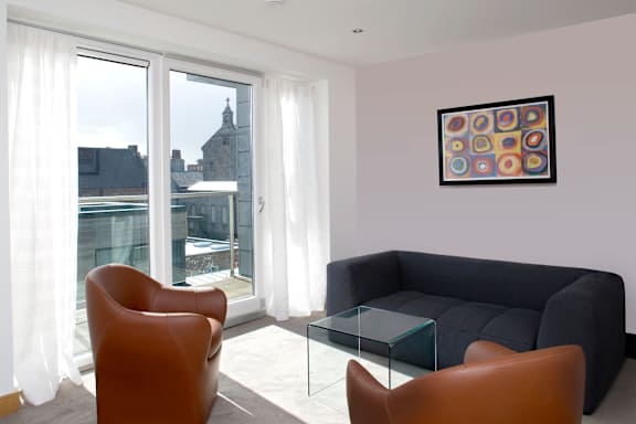 a living room with a black couch and a glass coffee table