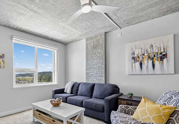 A living room with a grey sofa, a white coffee table, and a painting on the wall.