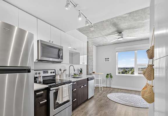 A modern kitchen with a stainless steel refrigerator and wooden flooring.
