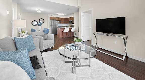 A modern living room with a grey couch and a glass coffee table.