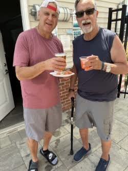 Two men are standing outside holding drinks.