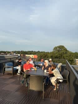 A group of people are sitting around a table on a wooden deck.