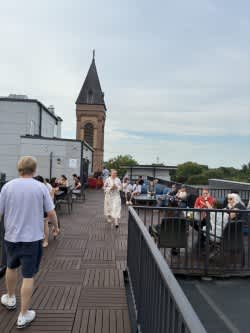 A man in a white shirt and blue shorts walks on a wooden deck.