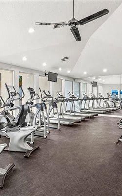 A gym with treadmills and a ceiling fan.