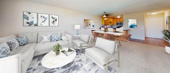 A living room with a white couch, a coffee table, and a dining table with chairs.