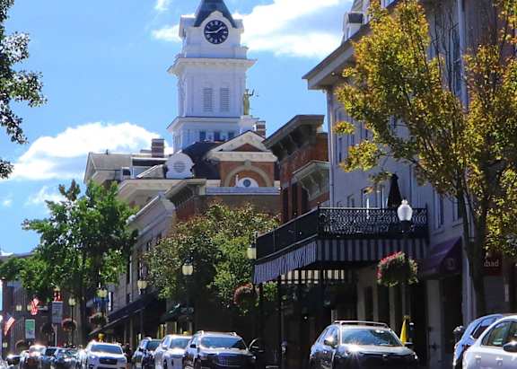 a city street with cars and a church with a clock tower