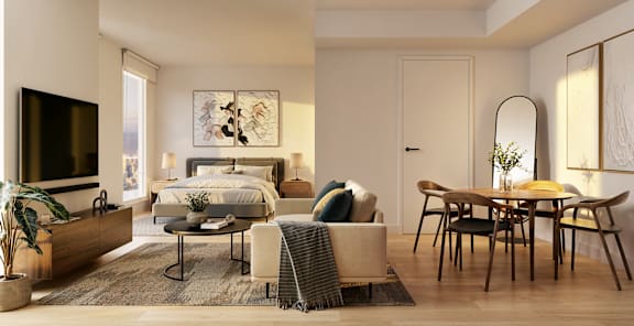 A modern bedroom with a large bed, a TV, a table and chairs, and a potted plant.