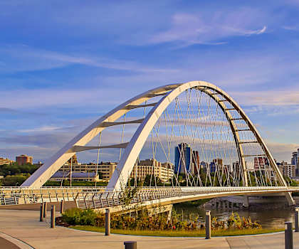 A modern bridge spans a river in a city.