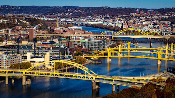 A yellow bridge crosses a river in a city.