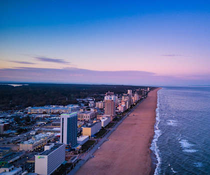 A beachfront cityscape at sunset with buildings lining the shore.