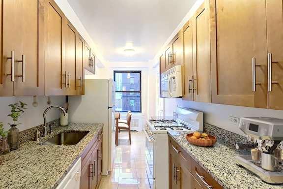 A kitchen with wooden cabinets and granite countertops.at Sutton Collection, New York, NY