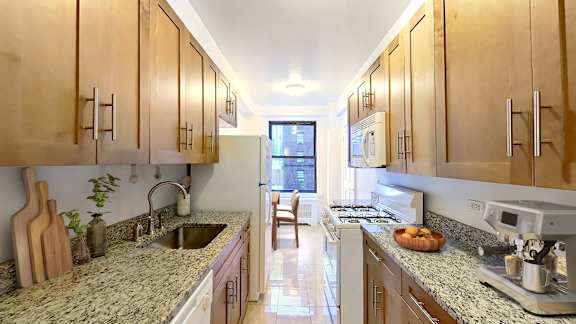 A kitchen with wooden cabinets and granite countertops.at Sutton Collection, New York, NY